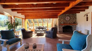 A cozy living room with wooden beams, a stone fireplace, and comfortable seating.
