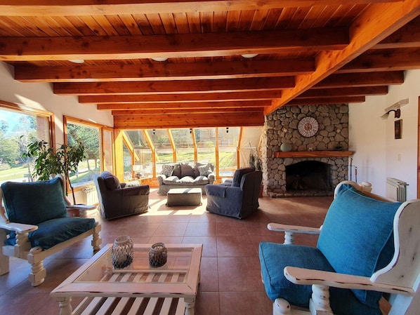 A cozy living room with wooden beams, a stone fireplace, and comfortable seating.
