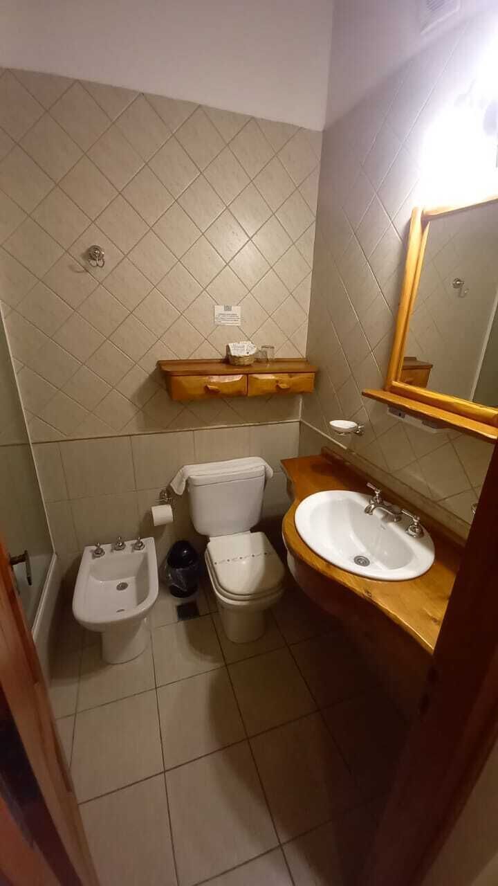 A bathroom with a toilet, bidet, sink, and mirror.