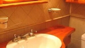 A bathroom with a wooden vanity, a sink, a mirror, and a toilet.