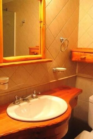 Et badeværelse med en trækommode, vask, spejl og toilet.