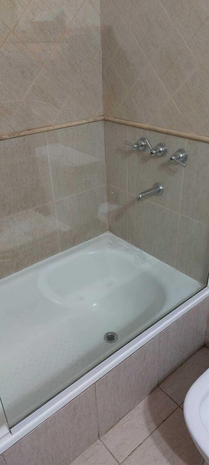 A bathroom with a glass-enclosed bathtub, a toilet, and a shower area.