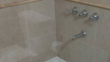 A bathroom with a glass-enclosed bathtub, a toilet, and a shower area.