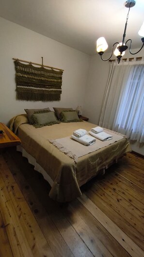 Une chambre avec un lit, une table de chevet, une tapisserie murale et un lustre.