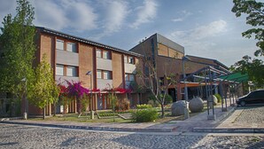 Un edificio moderno con fachada de ladrillo, amplias ventanas y un área de acceso cubierta.