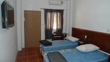 Una habitación pequeña y limpia con dos camas, un televisor y una puerta.