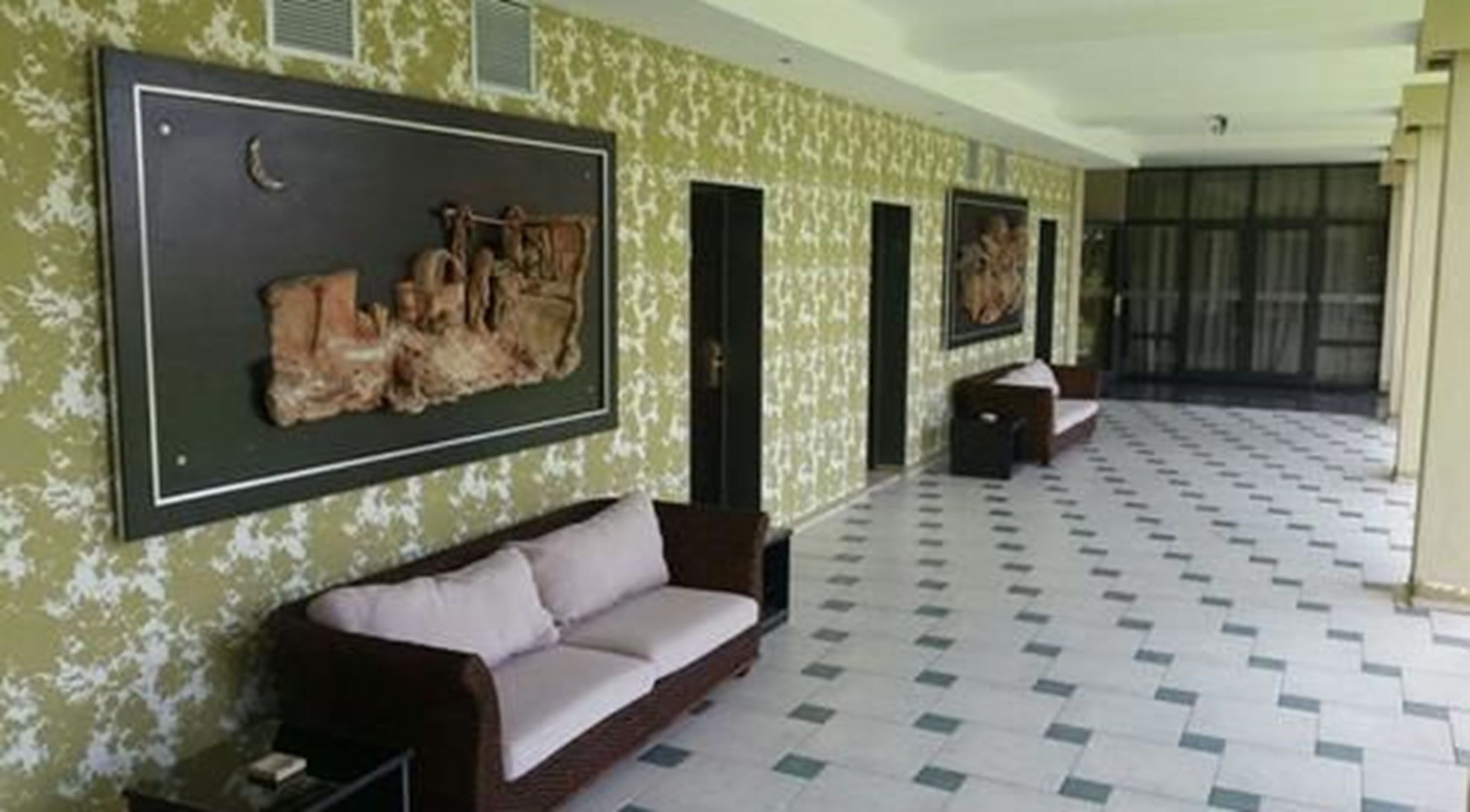 A spacious hallway with a patterned floor, a brown sofa with cushions, and two doors.