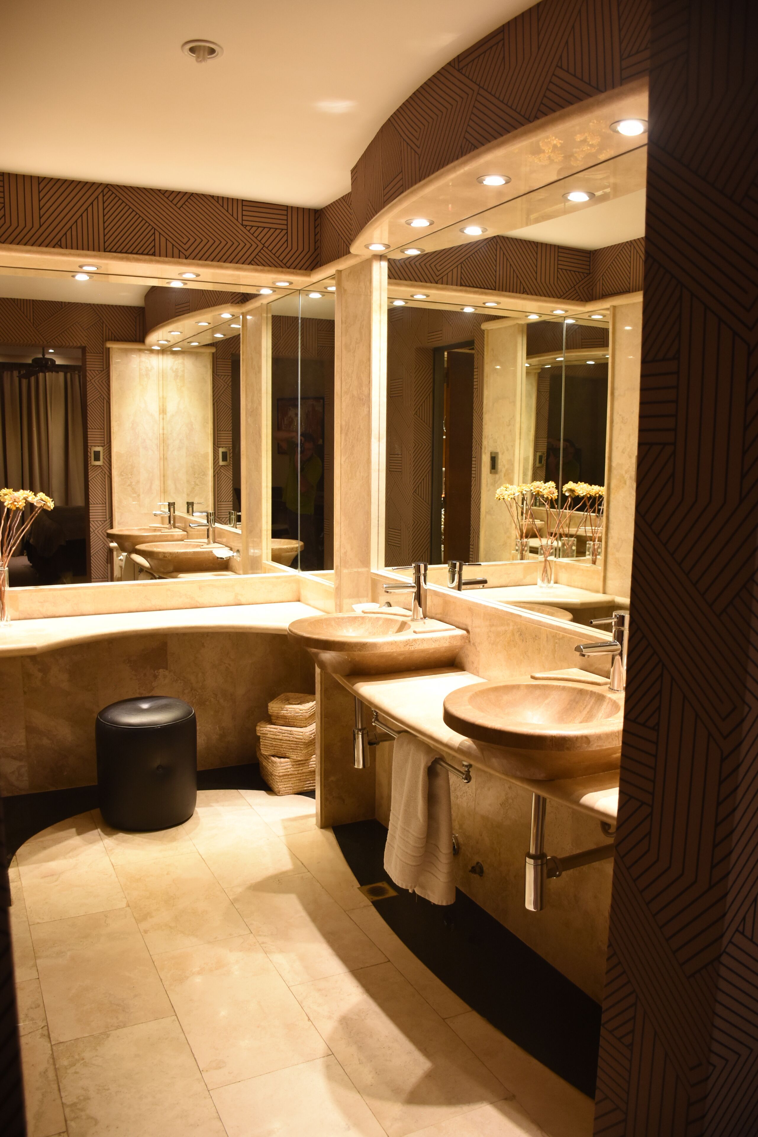 A modern bathroom with three sinks, large mirrors, and recessed lighting.