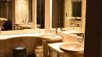 A modern bathroom with three sinks, large mirrors, and recessed lighting.