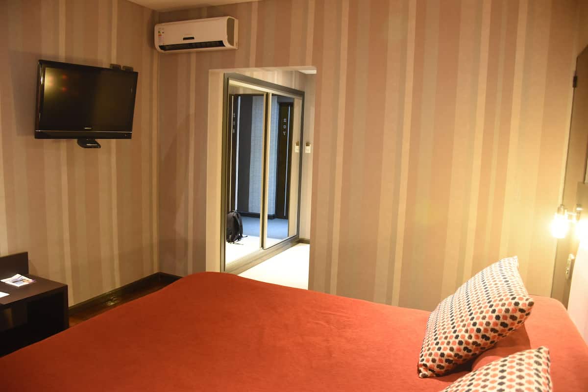 Een hotelkamer met een bed, een televisie en een deur naar een balkon.
