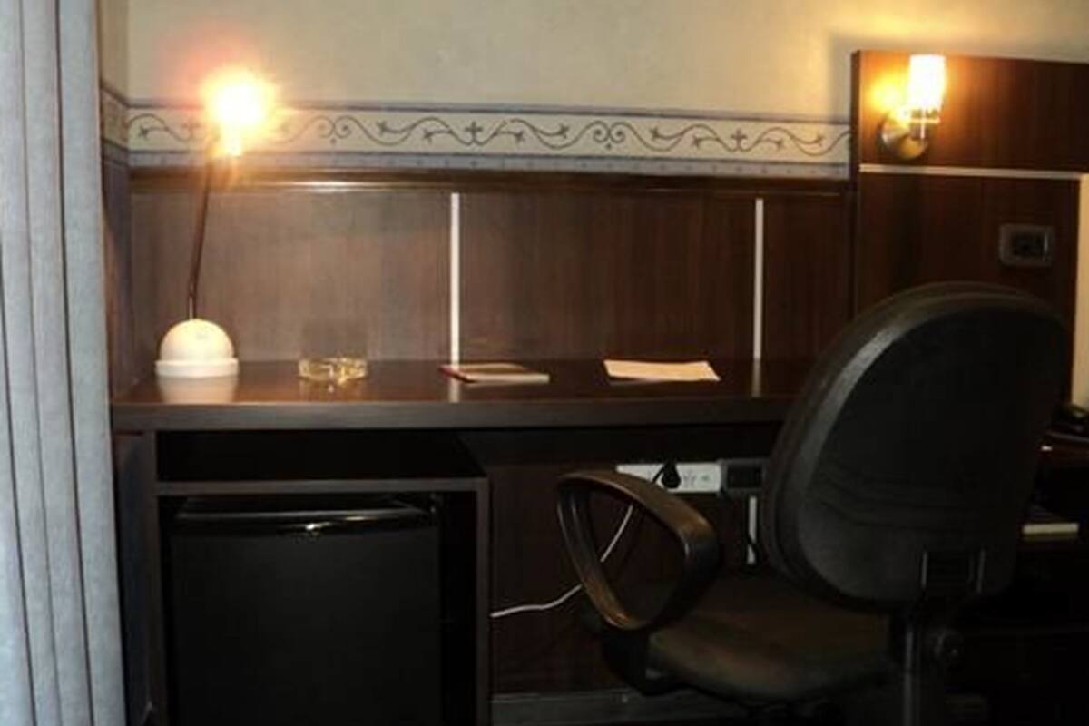 Een kleine kantoorruimte met een bureau, stoel en een afvalbak.