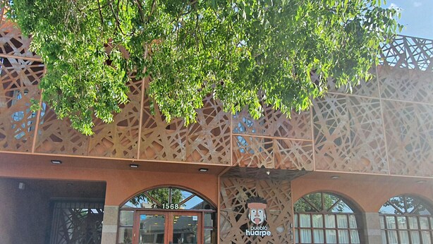 Un bâtiment avec un grand arbre devant, une enseigne avec le logo d’un chien et le numéro 1568.