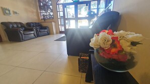 Un vaste espace de vie agrémenté d’une grande fenêtre, d’un canapé et d’un vase décoratif contenant des fleurs.