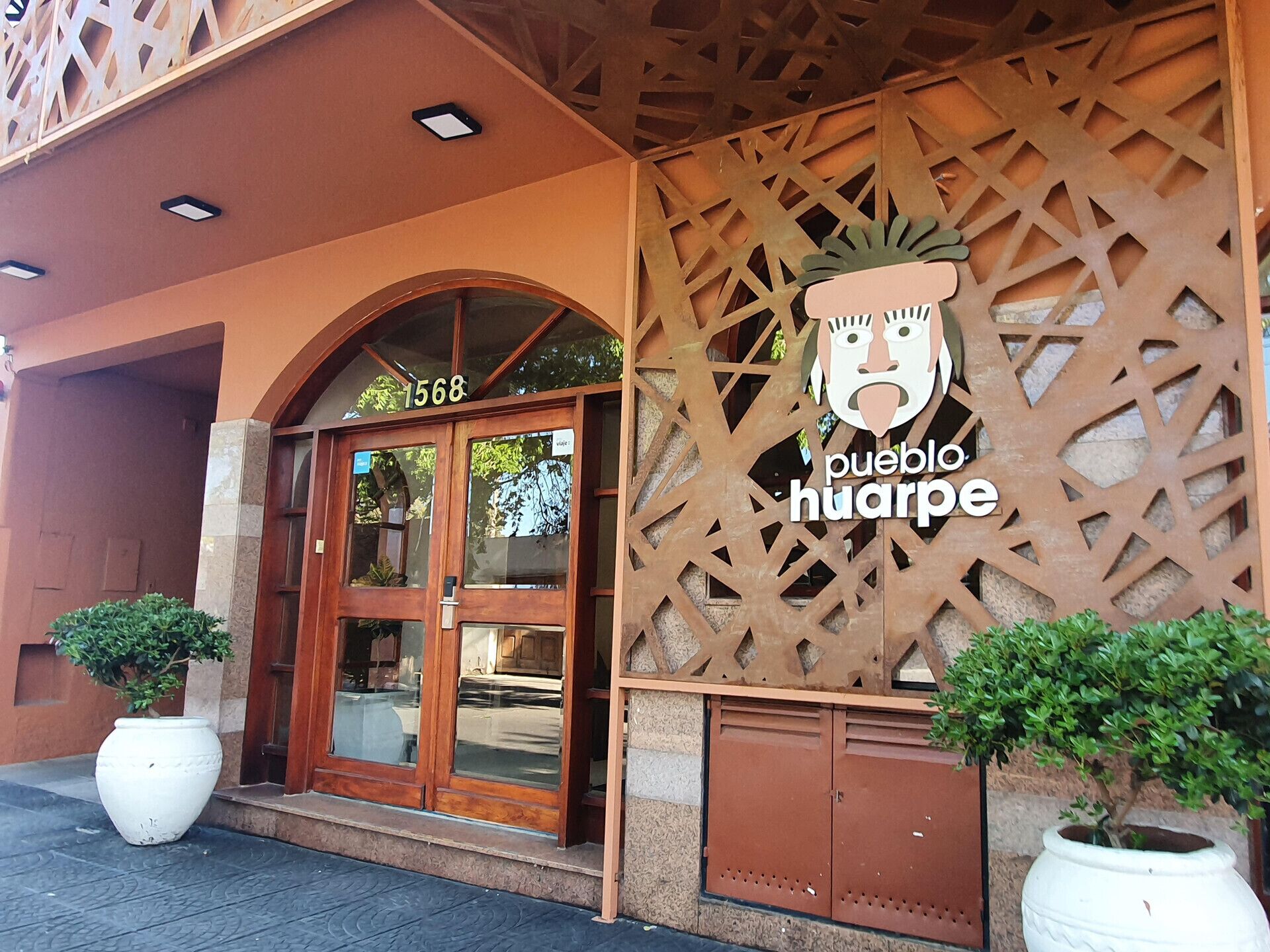Entrada de un edificio con una puerta de madera que lleva la etiqueta “1568” y un cartel que dice “pueblo huarpé”. 