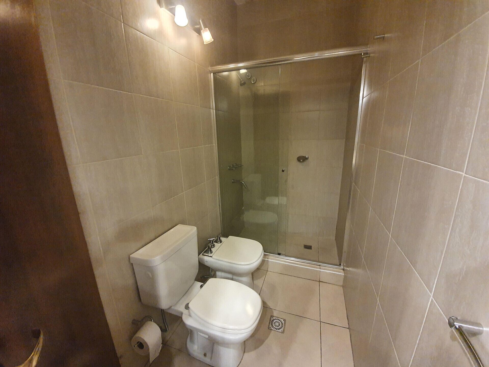 Kylpyhuoneessa on kaksi wc-istuinta, suihku ja wc-paperiteline.