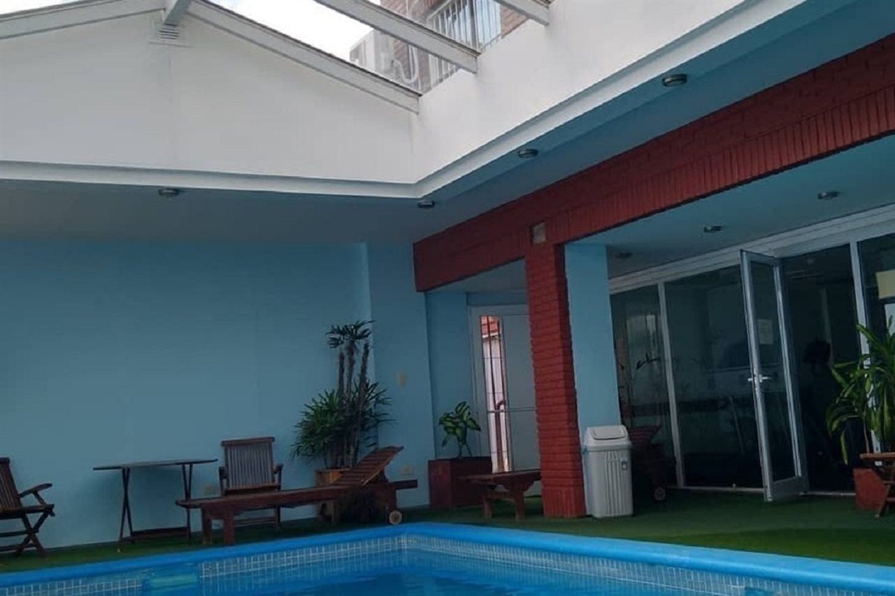 Un edificio moderno con piscina, mobiliario exterior y puerta de entrada de vidrio.