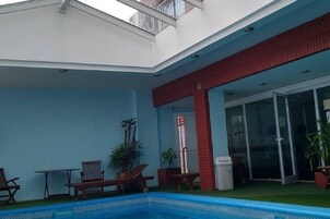 Un edificio moderno con piscina, mobiliario exterior y puerta de entrada de vidrio.