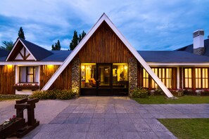 A wooden cabin with a stone facade, a front porch, and a well-lit entrance.