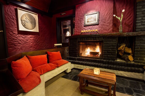 A cozy room with a fireplace, red walls, and a sofa with red cushions.