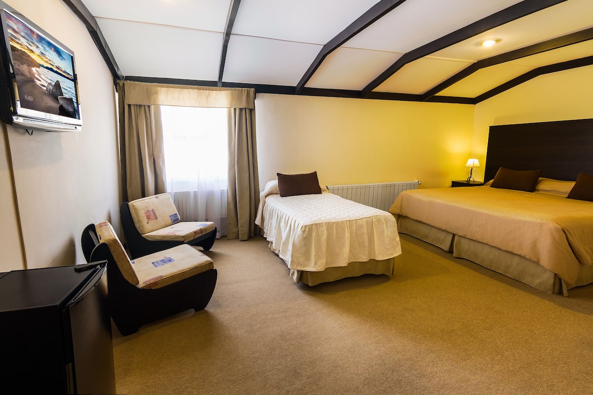 Une chambre d’hôtel avec un lit, une chaise, un bureau et un téléviseur.