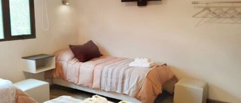 A hotel room with a bed, a TV, a bedside table, a chair, and a small table with towels.
