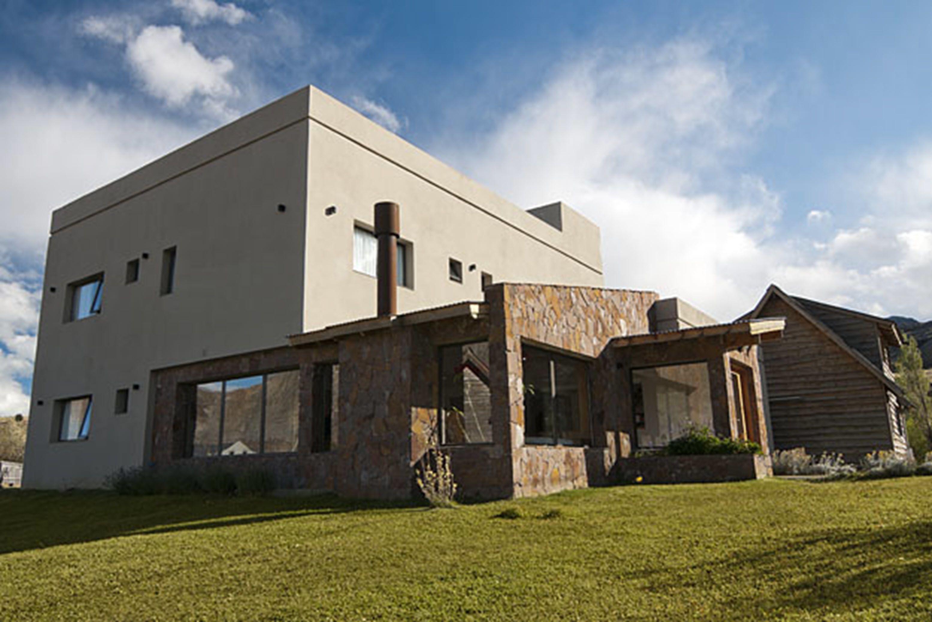 A modern building with a flat roof, large windows, and a stone facade.