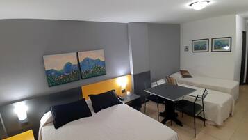 Habitación de hotel con una cama, un escritorio, una silla, una mesa y dos cuadros en la pared.