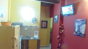 A compact kitchen with a refrigerator, microwave, sink, and a small wooden cabinet. - Los Pinos Apart Hotel (Ushuaia)