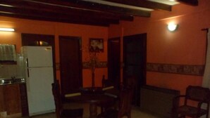 A compact kitchen with a refrigerator and a sink, a dining area with wooden chairs, and a tiled floor. - Los Pinos Apart Hotel (Ushuaia)