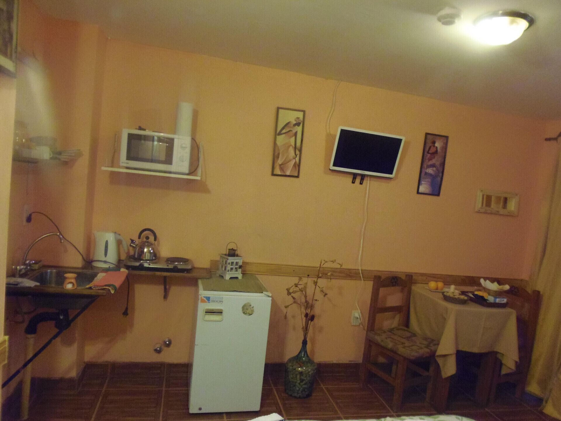A compact kitchen with a microwave, a small refrigerator, a sink, and a dining area with a table and chairs.