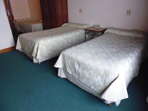 A room with two beds, a small table with a telephone, and a door.