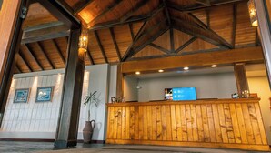 A reception area with a wooden reception desk, framed pictures on the wall, and a potted plant. - Tolkeyen (Ushuaia)