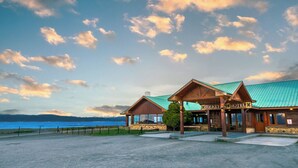 A wooden building with a green roof, labeled "Tolkey Hotel," by a body of water with a clear sky. - Tolkeyen (Ushuaia)