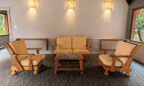 A room with a sofa, two armchairs, a coffee table, and three wall-mounted lights.