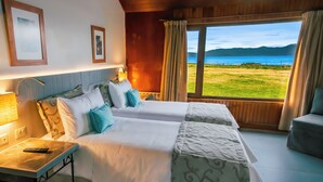 A hotel room with two beds, a desk, a lamp, and a view of the sea. - Tolkeyen (Ushuaia)
