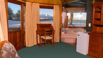 Ein Zimmer mit Schreibtisch aus Holz, Stuhl und Blick auf eine verschneite Landschaft durch große Fenster.