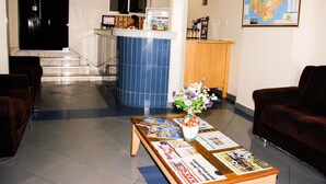 Ein Empfangsbereich mit einer Rezeption, einem Schwarzwert, einer Karte an der Wand und einem Couchtisch mit Zeitschriften und einem Blumenstrauß.
