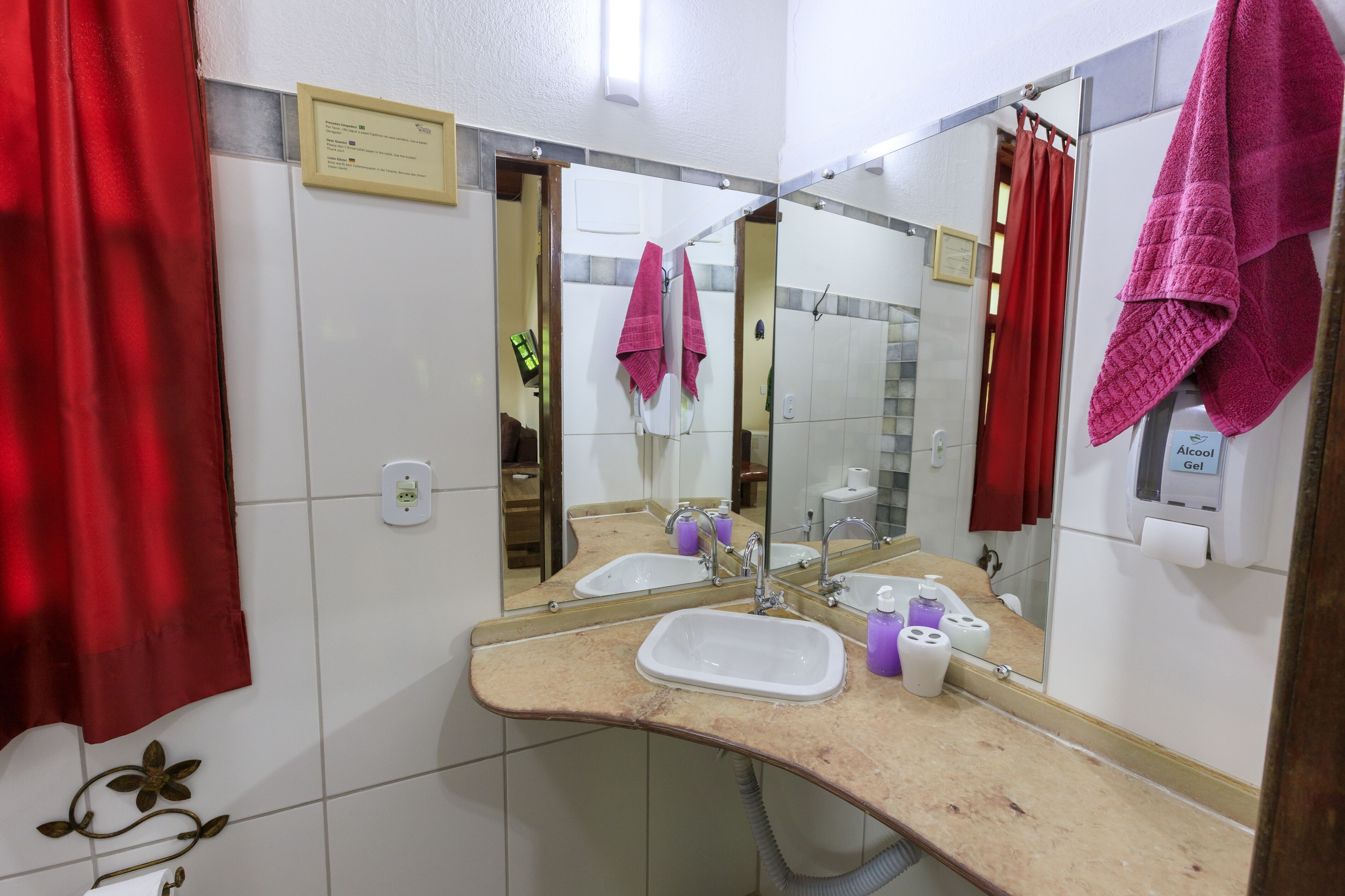 Casa de banho com duas pias, um espelho e uma cortina vermelha.