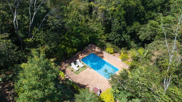 An aerial view of a square swimming pool surrounded by lush greenery and trees. - Pousada Canto no Bosque (Lençóis)