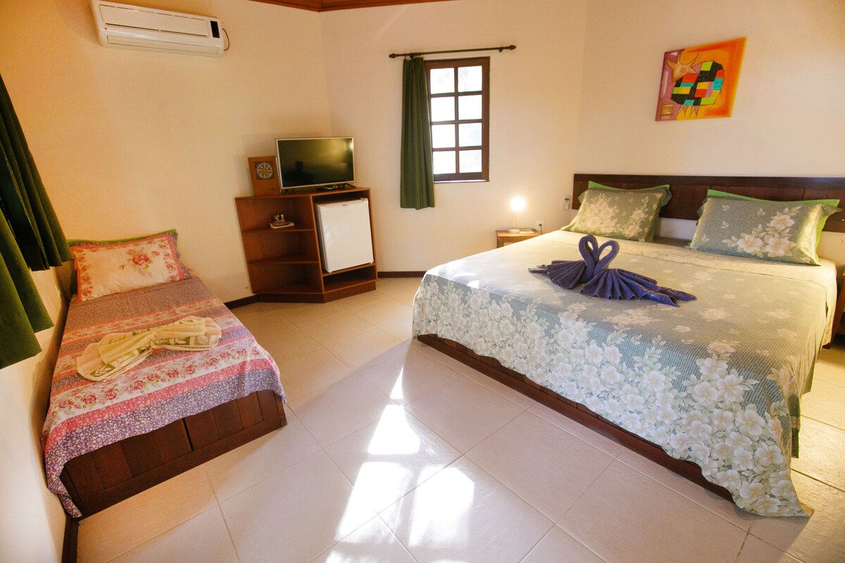 A hotel room with two beds, a TV, a small fridge, and a window with curtains.