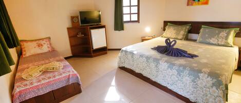 A hotel room with two beds, a TV, a small fridge, and a window with curtains.