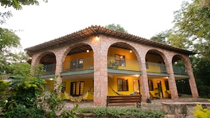 A two-story building with stone arches and balconies, surrounded by greenery. - Pousada Canto no Bosque (Lençóis)