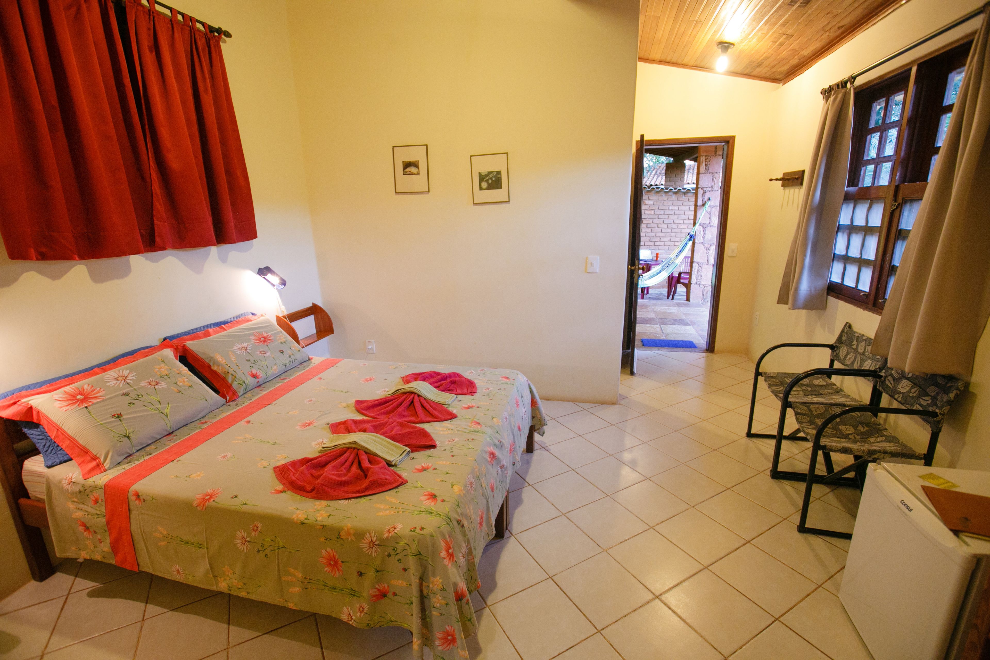 A bedroom with a bed, a chair, a small table, and a door leading to an outdoor area.