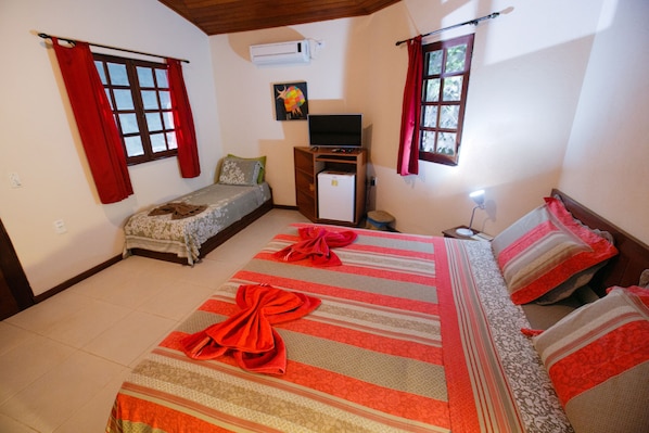 A hotel room with two beds, a TV, and a small desk. - Pousada Canto no Bosque (Lençóis)