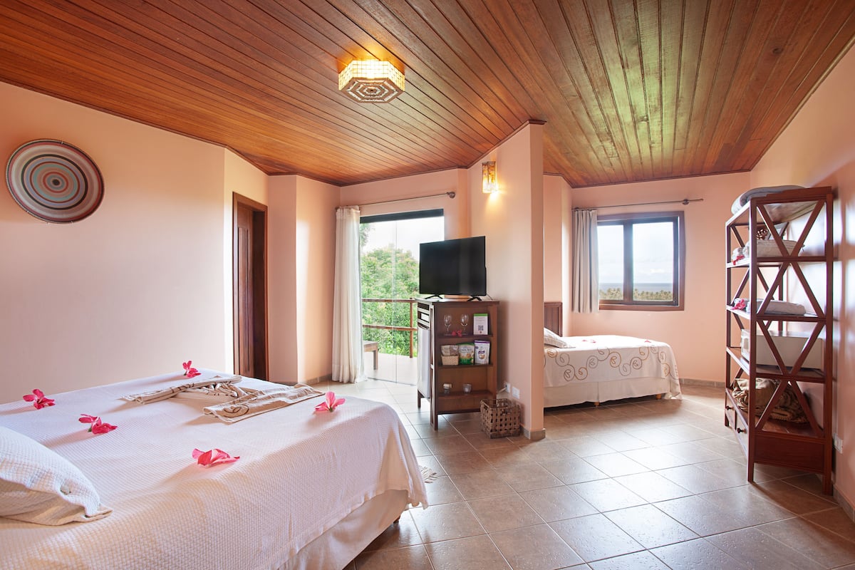 Une chambre avec un lit, une télévision, une étagère et un balcon.
