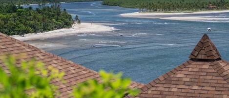 A coastal view with a river, beach, and forested area.
