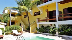 A two-story building with a yellow facade, a swimming pool, and a staircase leading to the upper floor. - Casa Grande & Senzala (Porto Seguro)