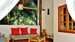 A room with a wooden bench, a woven stool, and a wooden door. - Casa Grande & Senzala (Porto Seguro)