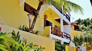 A two-story building with a yellow facade, a balcony, and lush greenery. - Casa Grande & Senzala (Porto Seguro)