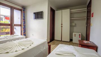 Habitación de hotel con dos camas, televisión, armario y un refrigerador pequeño.